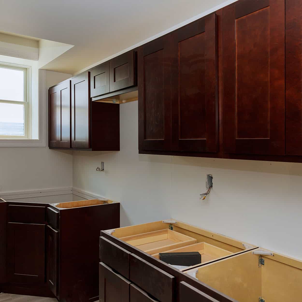 Wood kitchen cabinets being installed in an unfinished kitchen