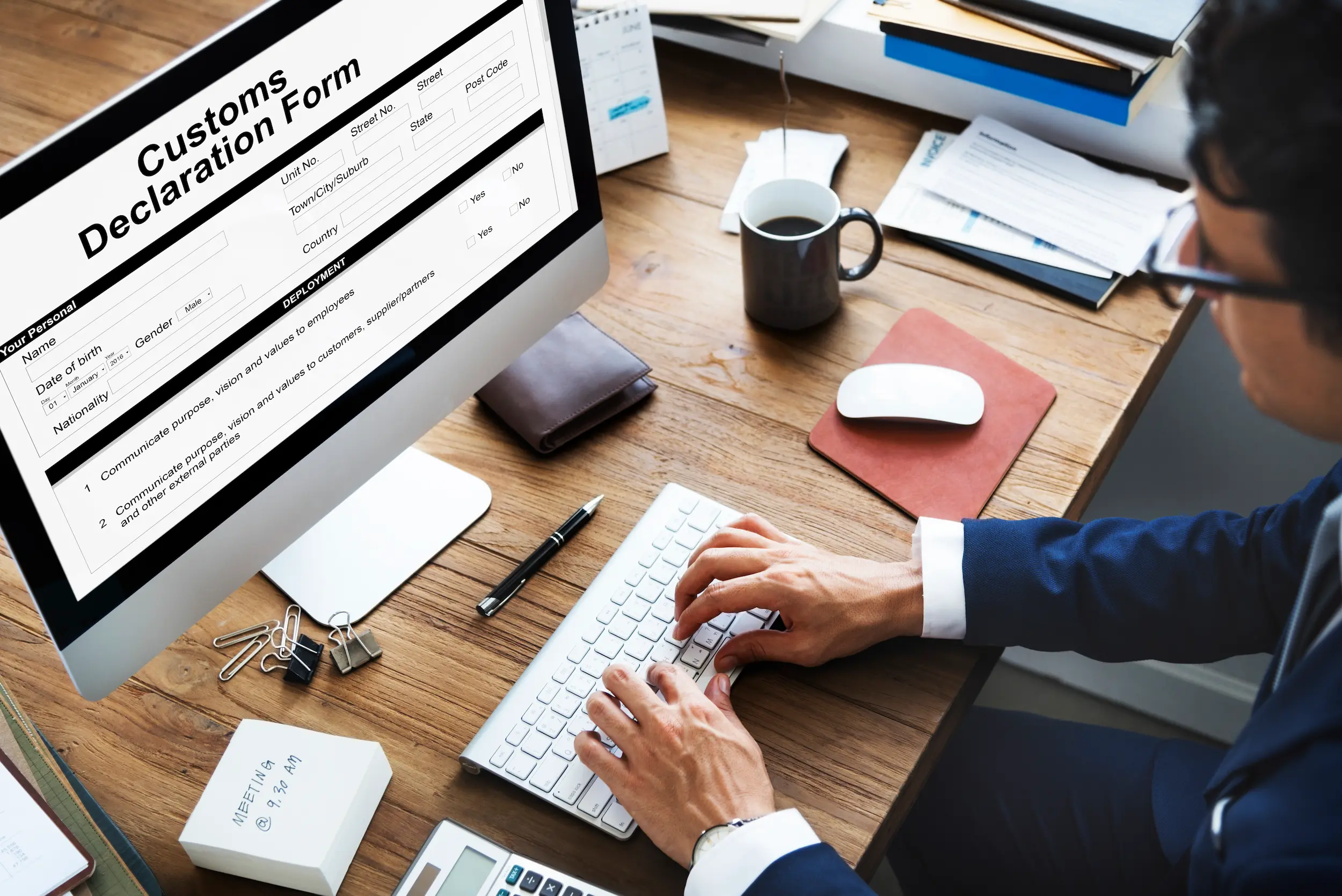 Trade specialist completing a customs declaration form on a desktop computer