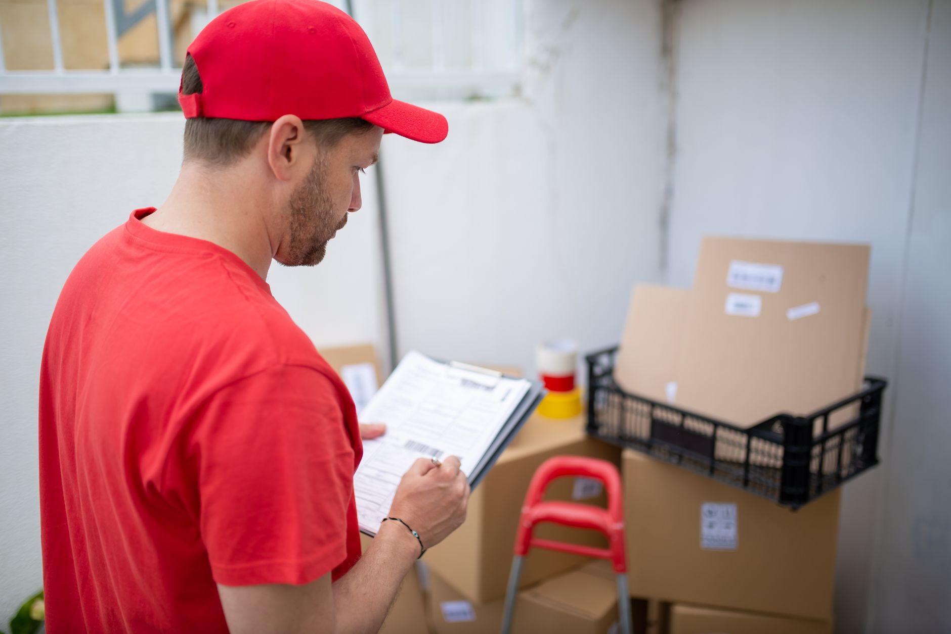 Courier checking shipment paperwork against parcels