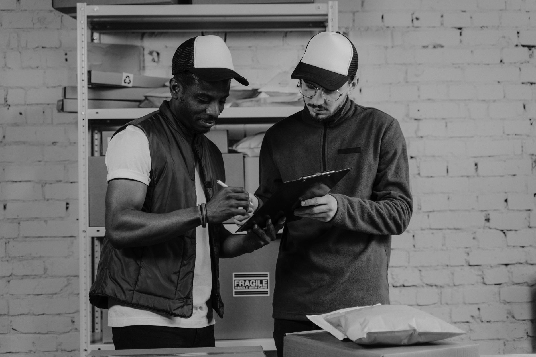 Two logistics workers checking parcel paperwork on a clipboard